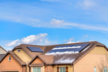 Focus on the snow dusted and wet roof of a house with installed solar panels