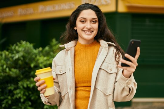 Young middle east woman using smartphone drinking coffee at the city.