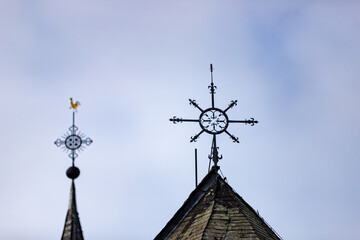 two peaks of a church roof, a golden weather cock is on top of the rear peak