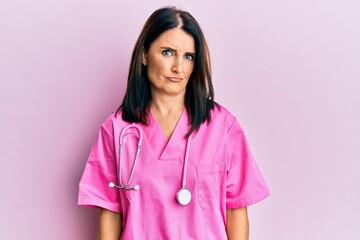 Middle age brunette woman wearing doctor uniform and stethoscope depressed and worry for distress, crying angry and afraid. sad expression.