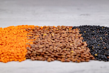 brown, red and black lentils on a wooden board
