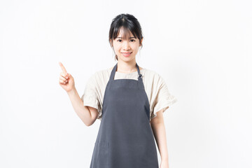 人差し指でポイントを示すエプロンを着た若い女性