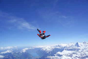 Skydivers perform tricks above snowcapped mountains
