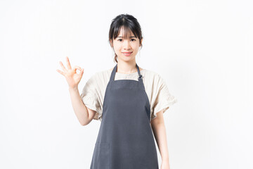 OKのジェスチャーをするエプロンを着た若い女性