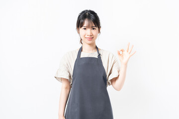 OKのジェスチャーをするエプロンを着た若い女性