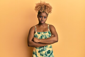 Young african woman with afro hair wearing summer dress skeptic and nervous, disapproving expression on face with crossed arms. negative person.