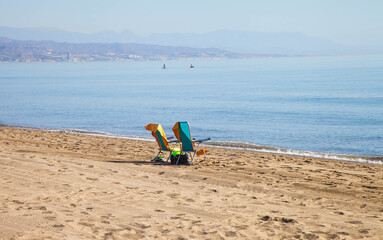 Fototapeta na wymiar Two deckchairs on golden sandy beach in Spain