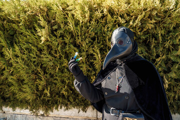 plague doctor holds a vaccine against a background of plants