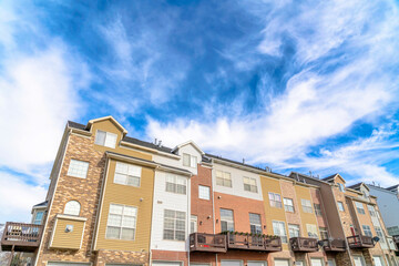 Fototapeta na wymiar Vivid blue sky and bright clouds over townhouses on scenic residential landscape