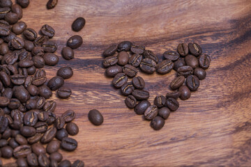 Heart made from coffee beans on a wooden board.
