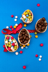 Chocolate easter eggs with bonbon and ribbon on blue background with copy space