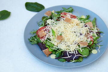 salad mix with avocado tomatoes with grated cheese and croutons on an empty light background