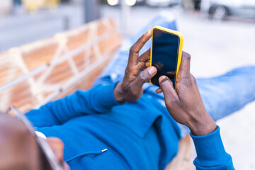 Black Man Using Cellphone Wearing Blue Sweater Outdoors.