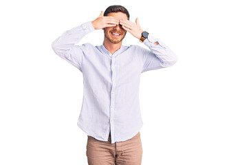 Fototapeta premium Handsome young man with bear wearing elegant business shirt and glasses covering eyes with hands smiling cheerful and funny. blind concept.