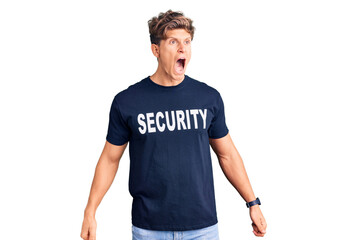 Young handsome man wearing security t shirt angry and mad screaming frustrated and furious, shouting with anger. rage and aggressive concept.