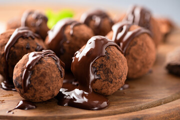 Sweet chocolate truffles with chocolate glaze on a wooden background, closeup view
