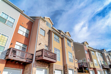 Sunny day view of townhouses with balconies over entrances to attached garages
