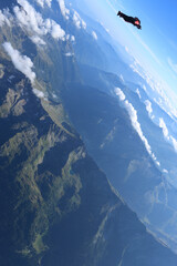 Wingsuit flier glides high above mountains