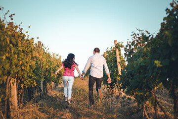 Young, romantic couple running through the vineyard