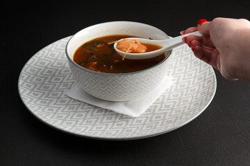 Miso soup with salmon in a white plate on a black background