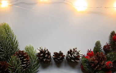 Festive background composition with snow covered red holly berries, fir tree branches and cones on...