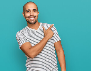 Hispanic adult man wearing casual clothes cheerful with a smile of face pointing with hand and finger up to the side with happy and natural expression on face