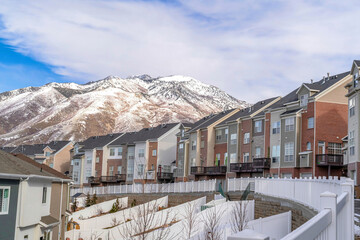 Fototapeta na wymiar Townhomes with snowy mountain peak and cloudy blue sky landscape in background