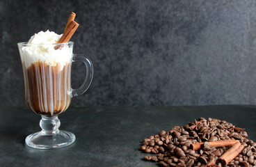 frothy coffee drink. Cappuccino or latte in a transparent glass on a dark background.