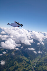 Obraz na płótnie Canvas Wingsuit flier glides high above land