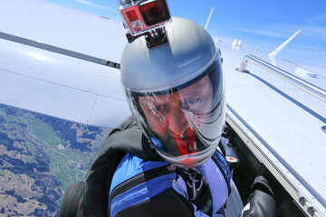 Portrait of wingsuit flier with camera jumping from airplane