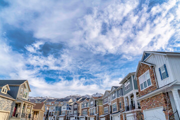 Fototapeta na wymiar Cloudy blue sky over houses with snowy mountain peak background in winter