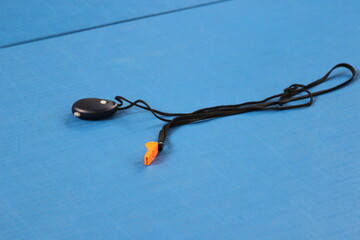 Coach's referee's whistle on blue tatami, isolated. High