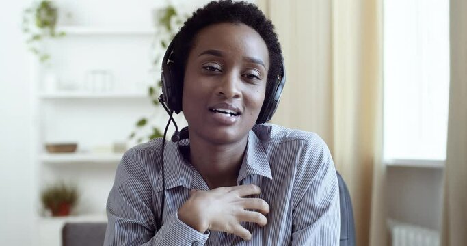 Webcam view african american business woman black mixed race ethnic female student wears headphones and head microphone speaks consultations remotely online for clients works speaks with colleagues