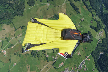 Wingsuit flier glides over mountains at sunrise