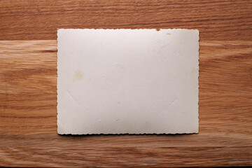 Mockup of vintage white paper list at textured wooden table background.