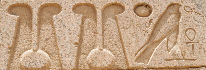ancient Egyptian hieroglyphs on the stone wall close-up banner