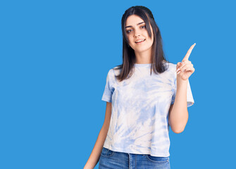 Young beautiful girl wearing casual t shirt pointing finger up with successful idea. exited and happy. number one.