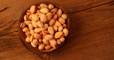Pistachio nuts in a container made of natural material on a wooden surface selective focus.