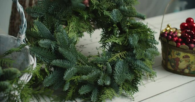 Making rustic christmas wreath. Woman holding green branches on rustic wooden background. Seasonal holiday workshop online, making festive decorations at home. High quality 4k footage