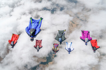 Team of wingsuit fliers glide in formation at sunset