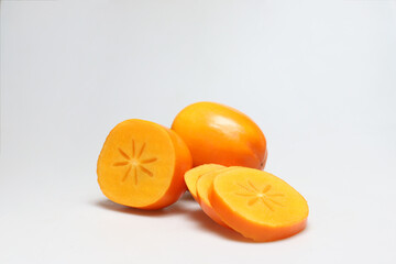 One whole with one half persimmon fruits and slices in front on white background - portrait