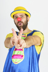 A clown in a bright blue and yellow suit shows a slingshot with his hands - aims