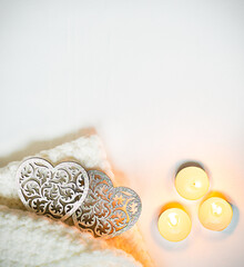 Valentines Day background with Carved wooden hearts, candles and soft white scarf