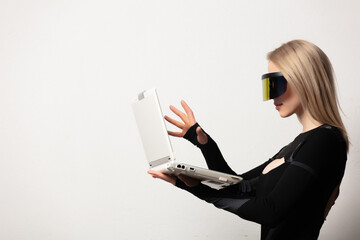 Blonde android female in VR glasses and laptop on white background.