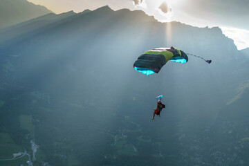 Parasailor glides over mountains at sunset