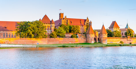 Obraz premium Panoramic view of the Teutonic Order Castle in Malbork during sunset.