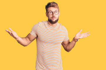 Young caucasian man wearing casual clothes and glasses clueless and confused expression with arms...