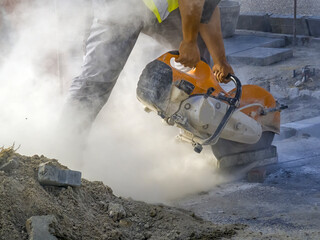 A worker cuts a tile to size with an electric grinder with many smoke. Pollution concept