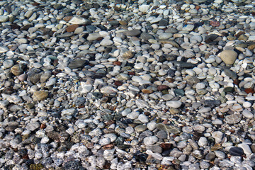 Pebbles in clear sea water in the sunlight