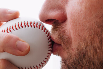 Athlete kisses a baseball for good luck before throwing - pitcher performs ritual while playing